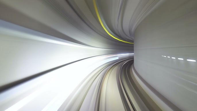 Long-exposure view through a curved tunnel with white and yellow light trails along the walls.